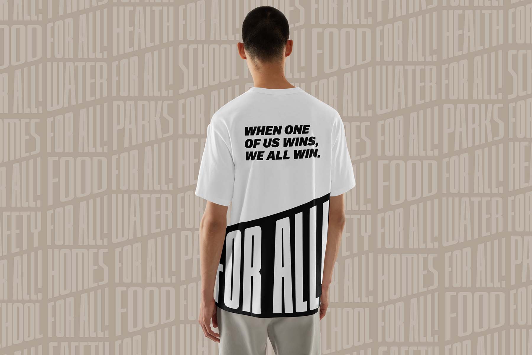 Mockup of man wearing a tshirt with the For All logo across the bottom and 'When one of us wins we all win' in large lettering arcoss the upper back.